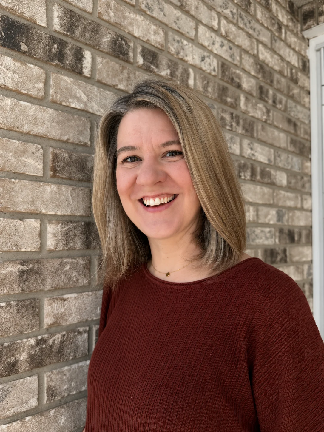 Kate Carlton smiling beside a brick wall